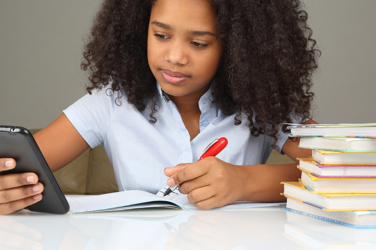 dark-skinned girl with smartphone doing homework